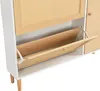 A close-up view of a white shoe cabinet with a rattan front and a wooden drawer that is partially open. Produktbild-Vorschau