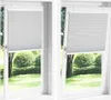 Two windows with white pleated blinds, one closed and one tilted open, showing a garden view. Anteprima dell’immagine prodotto