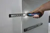 A hand holding a Bosch cordless screwdriver with a light illuminating a drawer slide. Voir les images du produit