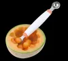 A melon baller tool is shown being used to scoop balls of melon from a halved cantaloupe. Produktbild-Vorschau
