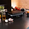 A kitchen counter with a grill, vegetables, and cooking ingredients. Voir les images du produit