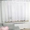 A white sheer curtain hangs over a window, with a radiator and part of a sofa visible below. Produktbild-Vorschau