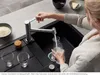 A person is filling a glass bottle with water from a kitchen faucet. Produktbild-Vorschau
