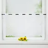 A white sheer curtain with a leaf pattern hangs in a window, with two sunflowers placed on the windowsill below. Produktbild-Vorschau
