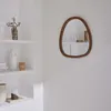 A mirror with a wooden frame is displayed on a white wall, next to a white shelf with decorative items. Anteprima dell’immagine prodotto