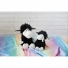 Two black sheep plush toys are sitting on a rainbow-colored fabric in front of a white brick wall. Produktbild-Vorschau