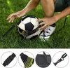A person's hands are shown interacting with a soccer ball training device on a grassy field. Náhľad obrázku produktu