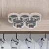 Five clear acrylic containers holding rolled belts are arranged on a wooden shelf. Below the shelf, several white shirts are hanging on hangers. Podgląd zdjęcia produktu