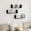 Three black U-shaped shelves mounted on a white wall above a sofa. Produktbild-Vorschau