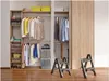 A closet interior with clothing and storage boxes, and two step stools in the foreground. Podgląd zdjęcia produktu
