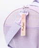 Close-up of a purple duffel bag with a pink tag and a purple strap. Produktbild-Vorschau