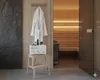 A spa or sauna room with a white bathrobe hanging on the wall and a white device on a wooden stool. Produktbild-Vorschau