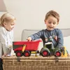 Two children playing with a toy tractor and trailer on a wicker chest. Produktbild-Vorschau