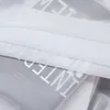 A close-up view of a transparent white voile curtain with printed text. Produktbild-Vorschau