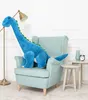 A large blue stuffed dinosaur is sitting on a light blue armchair in a room. Náhľad obrázku produktu