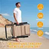 A man holding a folded beach chair on a sandy beach with the ocean in the background. Produktbild-Vorschau
