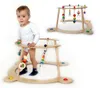 A baby is using a wooden walker with attached toys. Another walker is shown in the background. Produktbild-Vorschau