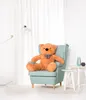 A large teddy bear sits in a teal armchair in a well-lit room with white curtains. Podgląd zdjęcia produktu