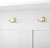 A close-up view of two gold double hooks mounted on a white wall. Anteprima dell’immagine prodotto