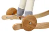 A close-up view of the wooden base and wheels of a rocking horse, with the legs of the toy visible. Podgląd zdjęcia produktu