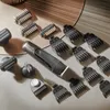 A collection of grooming tools, including a trimmer and various attachments, laid out on a textured surface. Produktbild-Vorschau