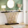 A modern console table with a black marble top and gold metal legs, decorated with a lamp, books, and a vase with dried flowers, placed in an entryway with a mirror on the wall and a white door. Produktbild-Vorschau