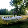 A picnic table set up outdoors with food and flowers. Náhľad obrázku produktu