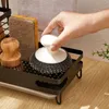 A hand is shown placing a scrub brush into a kitchen sink organizer. The organizer holds various cleaning tools like sponges and brushes. Voir les images du produit
