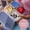 A child's hands are holding an open b.box snack box filled with food, including wraps, an apple, and yogurt with blueberries. A spoon is also visible. Anteprima dell’immagine prodotto