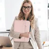 A woman in a business suit holds a pink laptop sleeve. Produktbild-Vorschau