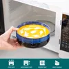 A hand is placing a bowl of soup into a microwave. Produktbild-Vorschau