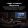 Three people are sitting on a couch watching a large screen displaying a school of fish. Produktbild-Vorschau