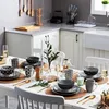 A dining table set for a meal with plates, bowls, cups, and cutlery, arranged in a kitchen setting. Náhled obrázku produktu