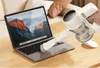 A hand is using a white handheld vacuum cleaner with a brush attachment to clean the keyboard of a laptop. Podgląd zdjęcia produktu