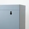 A close-up view of the corner of a gray metal cabinet, showing a keyhole-shaped mounting hole. Voir les images du produit