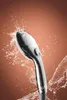 A chrome shower head spraying water against a brown background. Produktbild-Vorschau