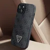 A black Guess iPhone case with a repeating logo pattern rests on a textured beige surface, possibly car seats. Voir les images du produit