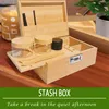 A wooden stash box with accessories and jars is displayed on a table, with text overlays. Produktbild-Vorschau