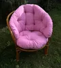 A pink cushion on a rattan garden chair, placed outdoors on grass. Produktbild-Vorschau