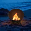 A fire pit with a fire burning on a beach at dusk. Produktbild-Vorschau