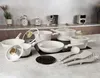 A collection of white cookware and kitchen utensils arranged on a countertop. Produktbild-Vorschau