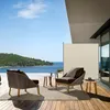 A patio scene with outdoor furniture and a view of the ocean. Produktbild-Vorschau