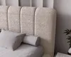 A close-up view of a bed with a textured boucle headboard and gray pillows. Náhled obrázku produktu