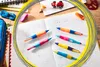 A close-up shot of several colorful pens scattered on an open notebook with handwriting, surrounded by a yellow and gray circular overlay. Anteprima dell’immagine prodotto