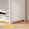 Close-up of the bottom of a white modular closet, showing its feet and a stack of books on a shelf. Podgląd zdjęcia produktu