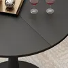 A close-up view of a dark-colored round table with two wine glasses and a decorative tray with a silver sphere on it. Anteprima dell’immagine prodotto