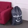 A laundry bag with a smiley face and the words 'wash me' is placed next to a red sofa. Produktbild-Vorschau