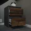 A bedside table with two drawers, one of which is partially open, sits in a room with gray walls and a tiled floor. An alarm clock is on top of the table. Voir les images du produit
