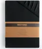 A folded black fitted sheet with a brown paper band around it, showing branding and product details. Produktbild-Vorschau