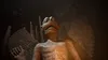 A stone gargoyle statue with wings in a dark, cave-like setting, illuminated by warm light. Produktbild-Vorschau